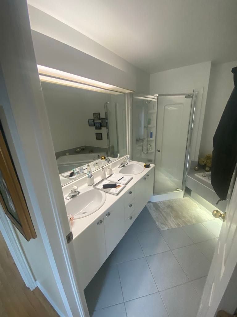 Une salle de bain avec deux lavabos, une douche et un grand miroir.