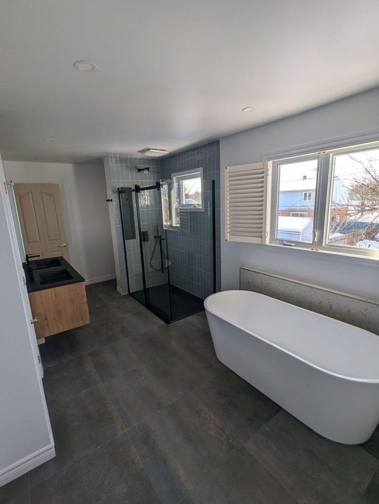 Une salle de bain avec baignoire, lavabo, douche et fenêtre.