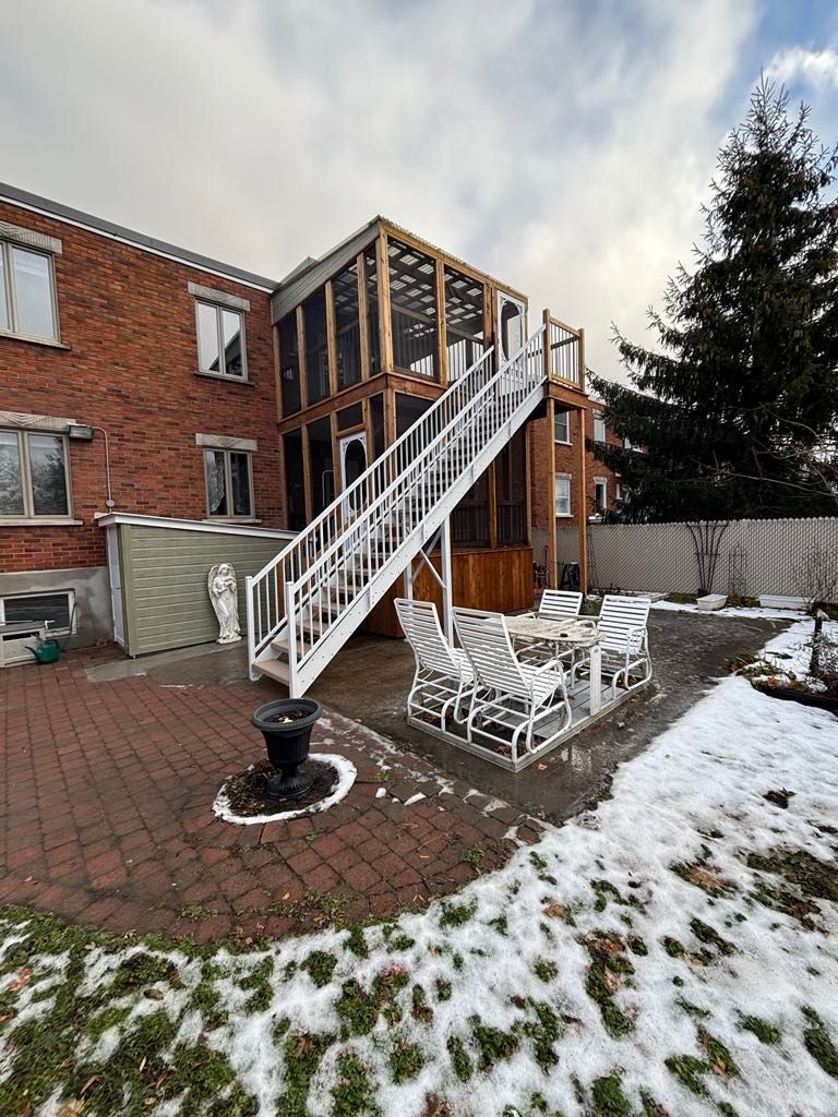 Une maison en briques avec une terrasse et des escaliers dans l'arrière-cour.