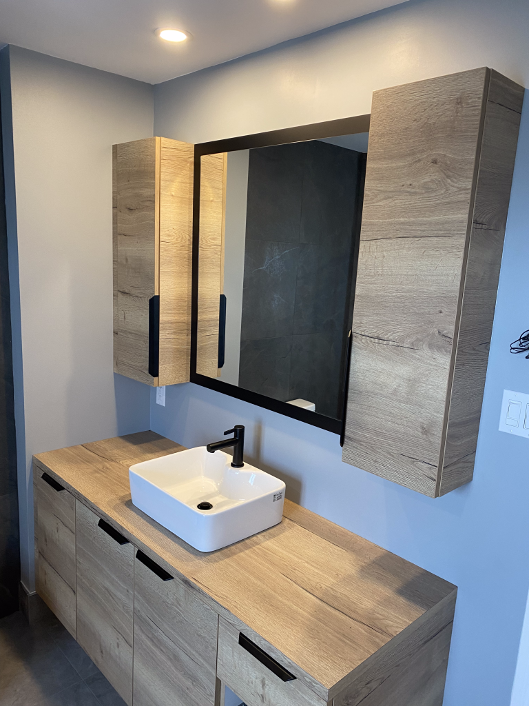 Une salle de bain avec un lavabo, un miroir et des armoires.