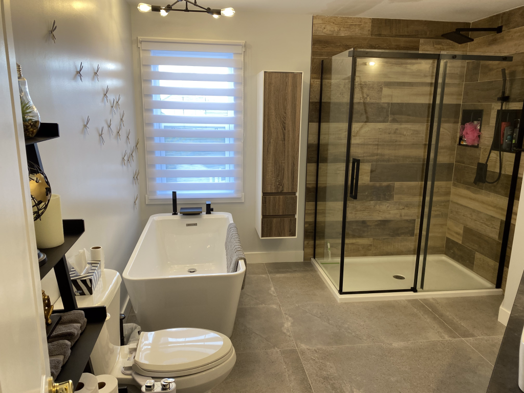 Une salle de bain avec baignoire, WC, douche et fenêtre.