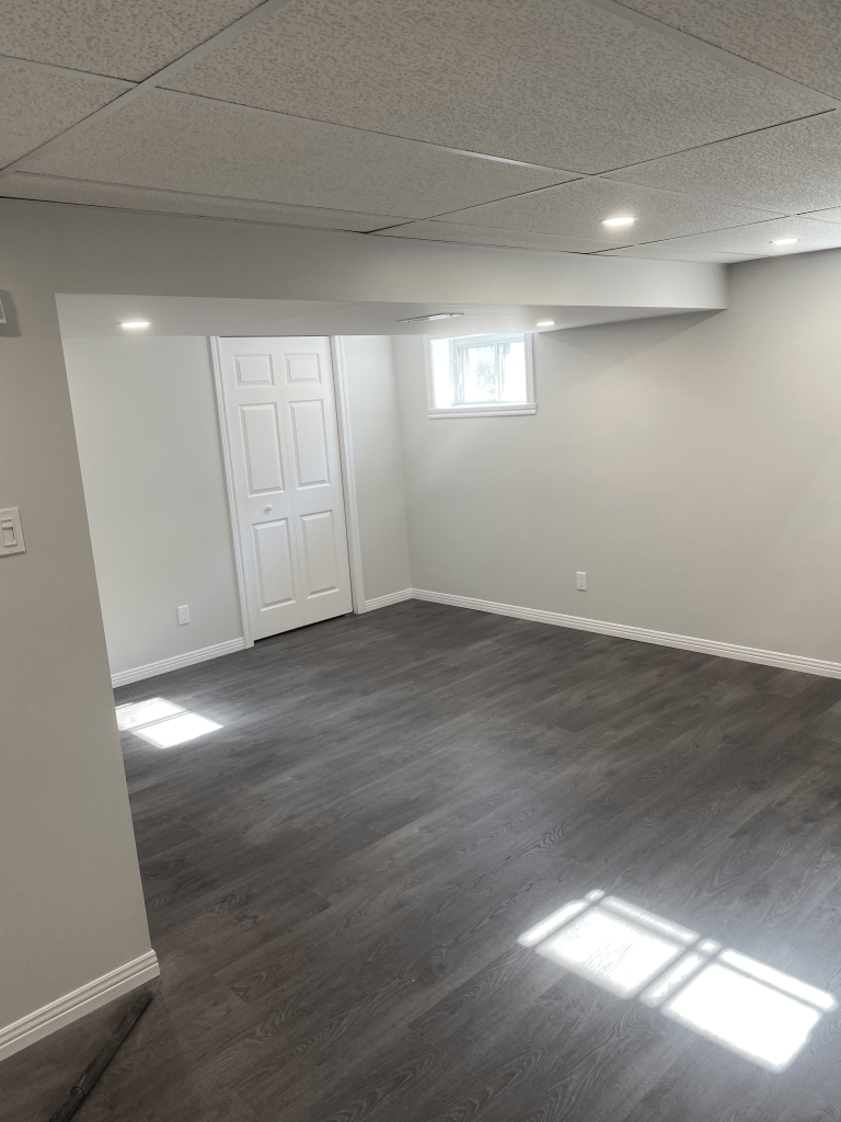 Un sous-sol vide avec planchers de bois franc et une fenêtre.