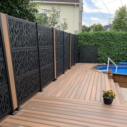 Une terrasse en bois avec une clôture et une piscine en arrière-plan