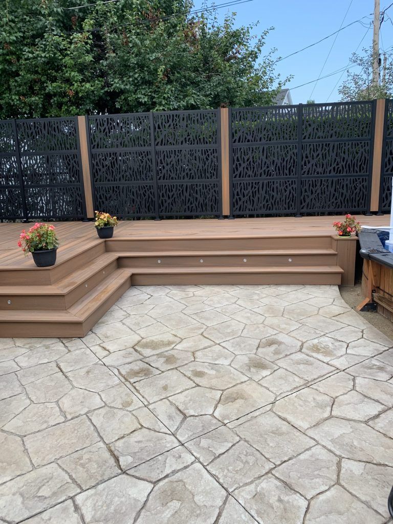 Un patio avec une terrasse en bois et des marches qui y mènent.