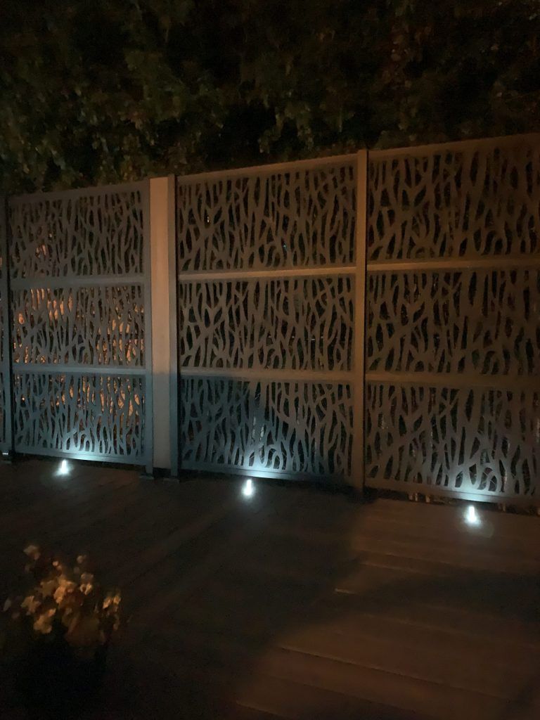 Une clôture avec un motif dessus est éclairée la nuit.