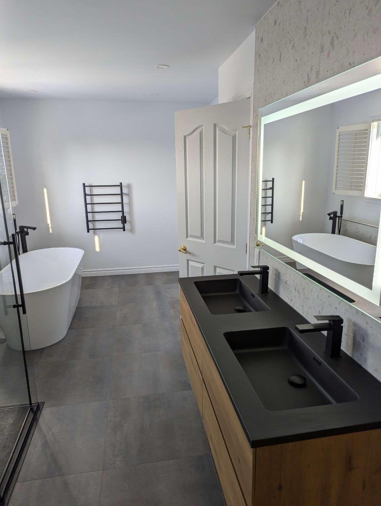 Une salle de bain avec deux lavabos, une baignoire et un miroir.