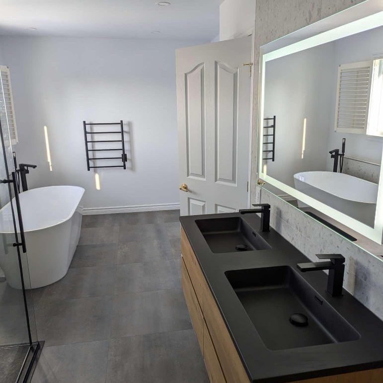 Une salle de bain avec deux lavabos, une baignoire et un miroir.