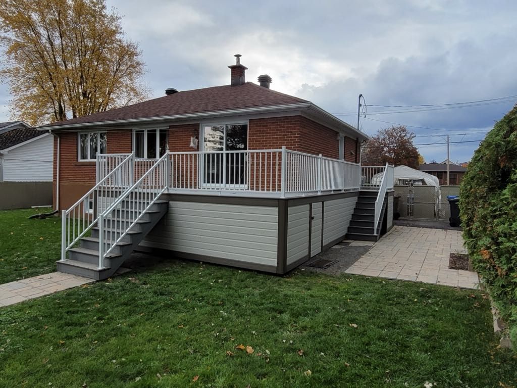 Une petite maison en briques avec une grande terrasse et des escaliers.