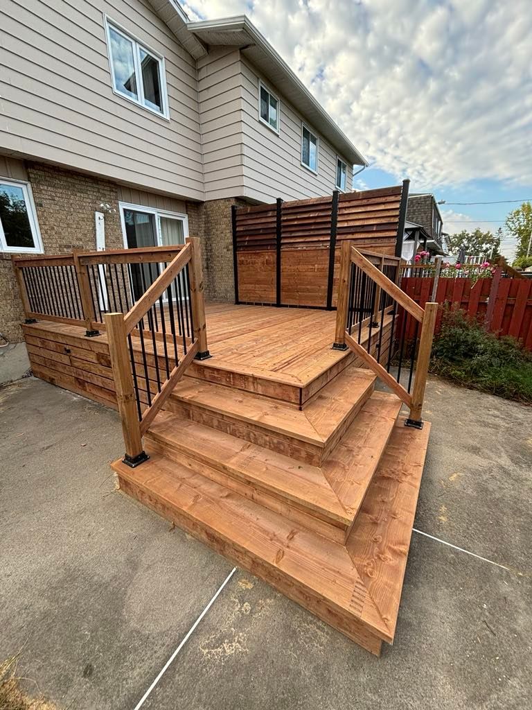 Une terrasse en bois avec des escaliers et une clôture devant une maison.