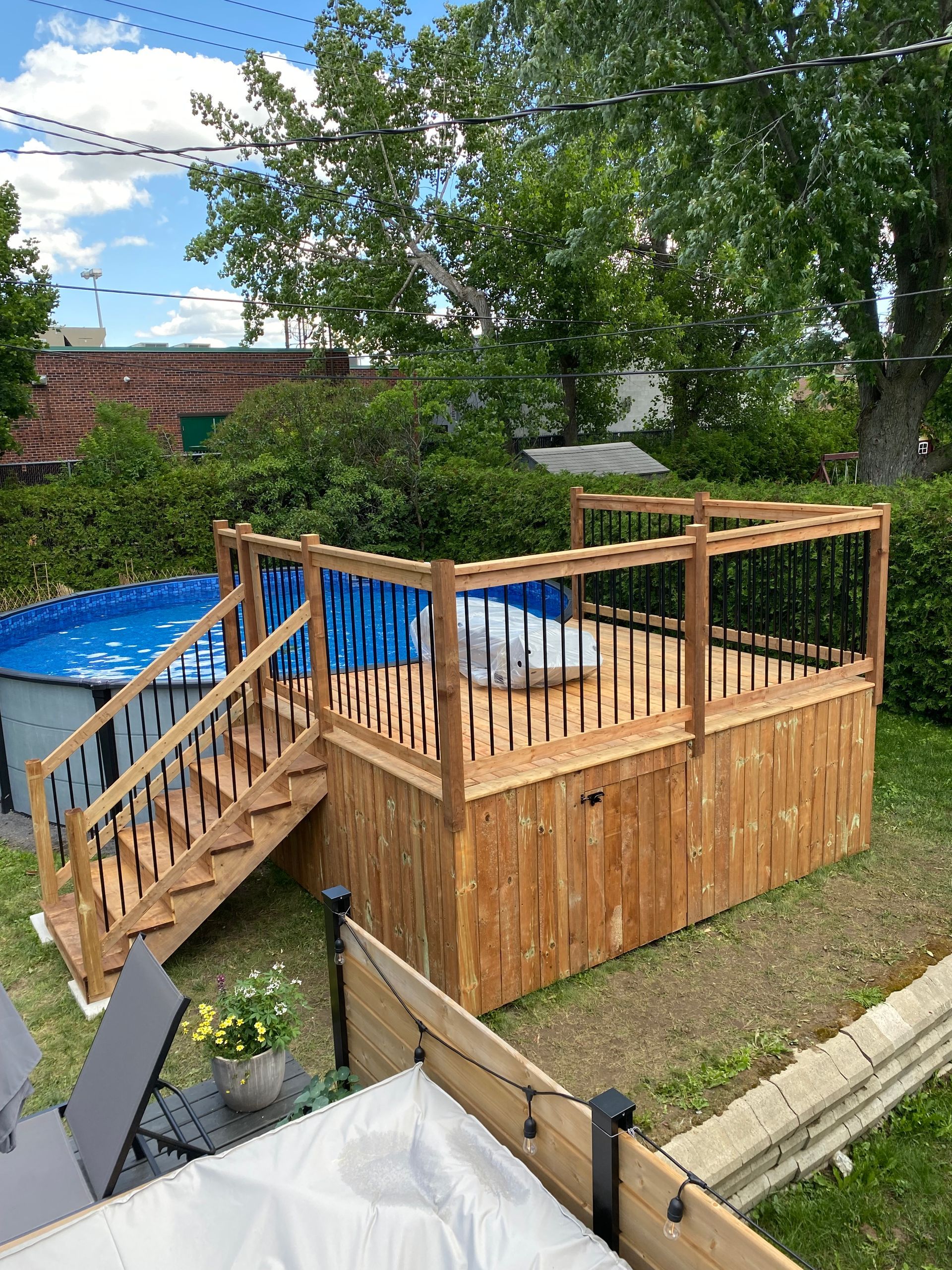Une terrasse en bois avec des escaliers menant à une piscine dans une cour arrière.