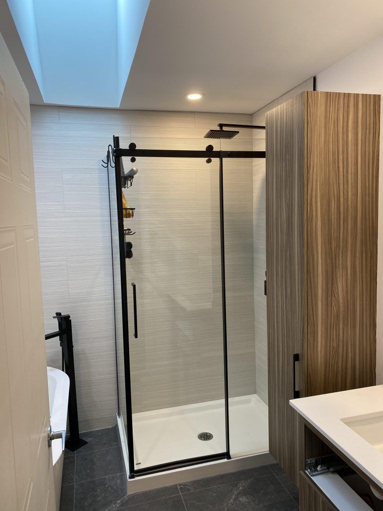 Une salle de bain avec une porte de douche coulissante en verre et un lavabo.