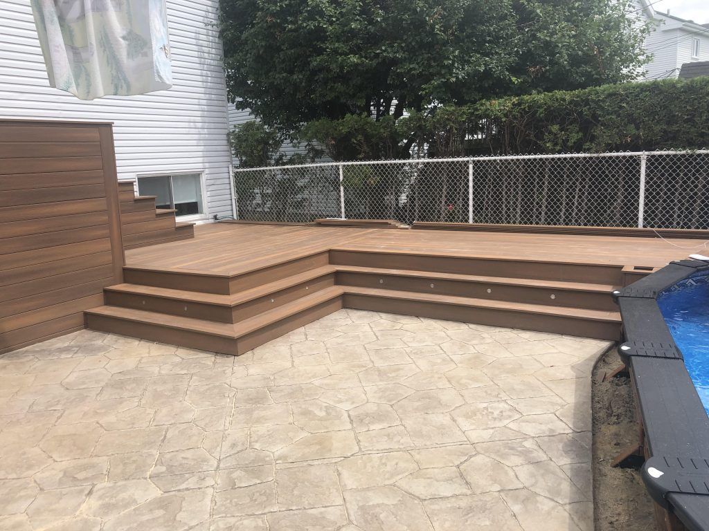 Une terrasse en bois avec des escaliers menant à côté d'une piscine.