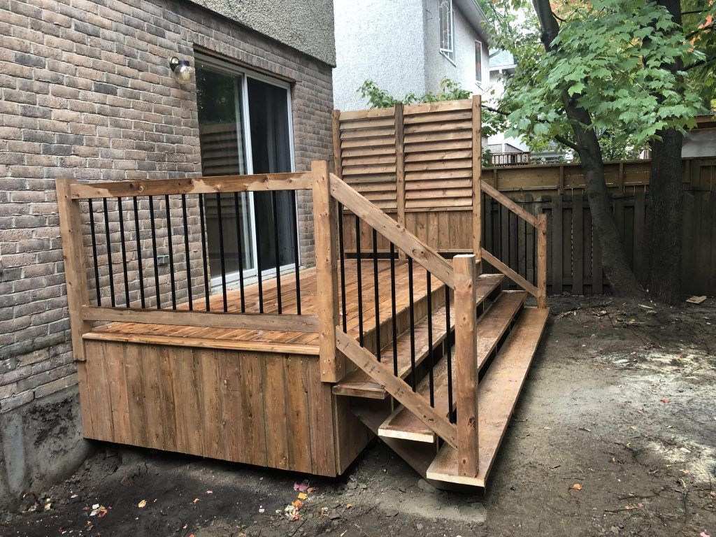 Une terrasse en bois avec des escaliers qui y mènent se trouve dans l'arrière-cour d'une maison.