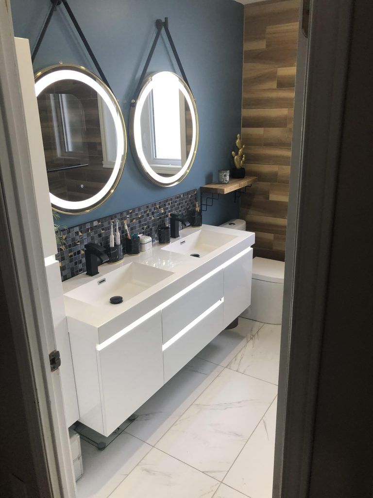 Une salle de bain avec deux lavabos, deux miroirs et un WC.