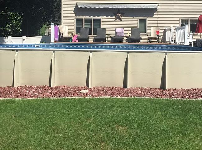 A large swimming pool is in the backyard of a house.