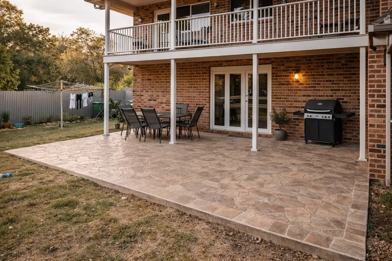 New backyard patio pad with dining set, bbq, and second-story balcony on a brick house in Toowoomba