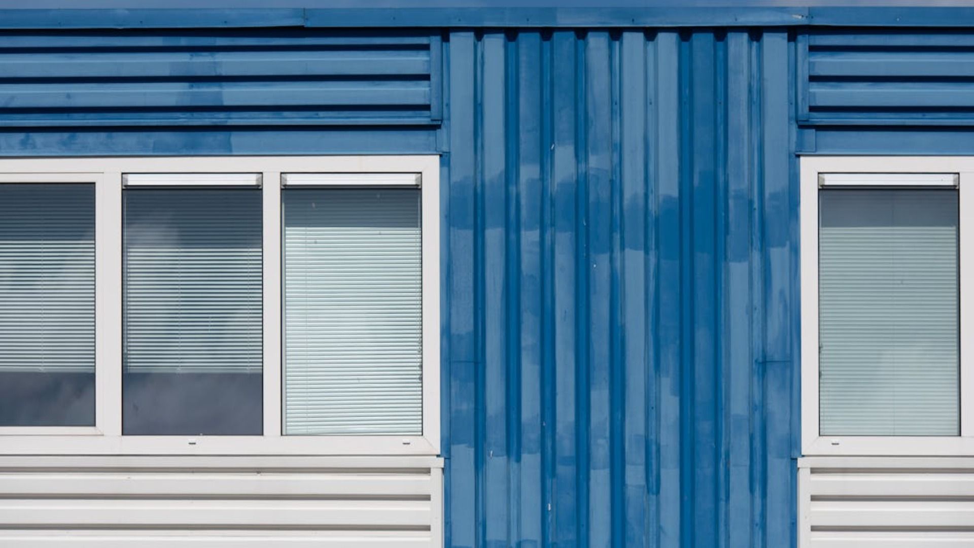 Un edificio azul con ventanas blancas y revestimiento azul.