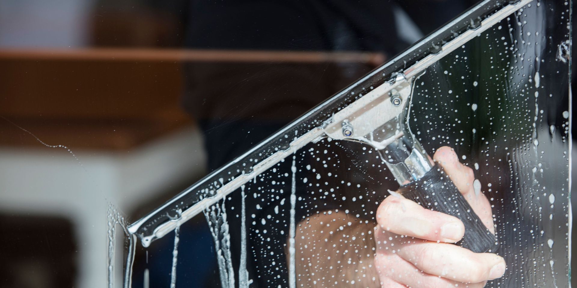 A person is cleaning a window with a squeegee.