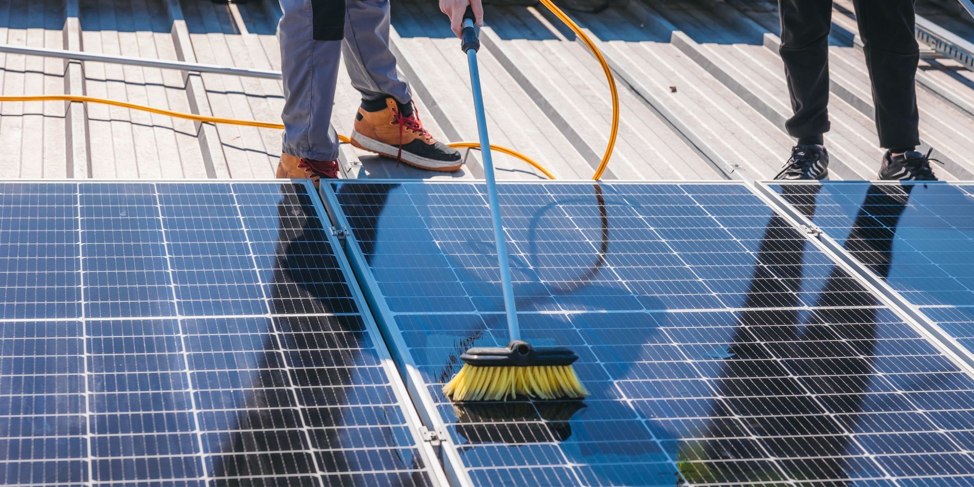 A person is cleaning a solar panel with a broom.