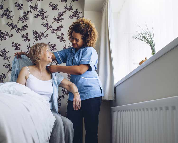Nurse helping elderly woman up from a bed
