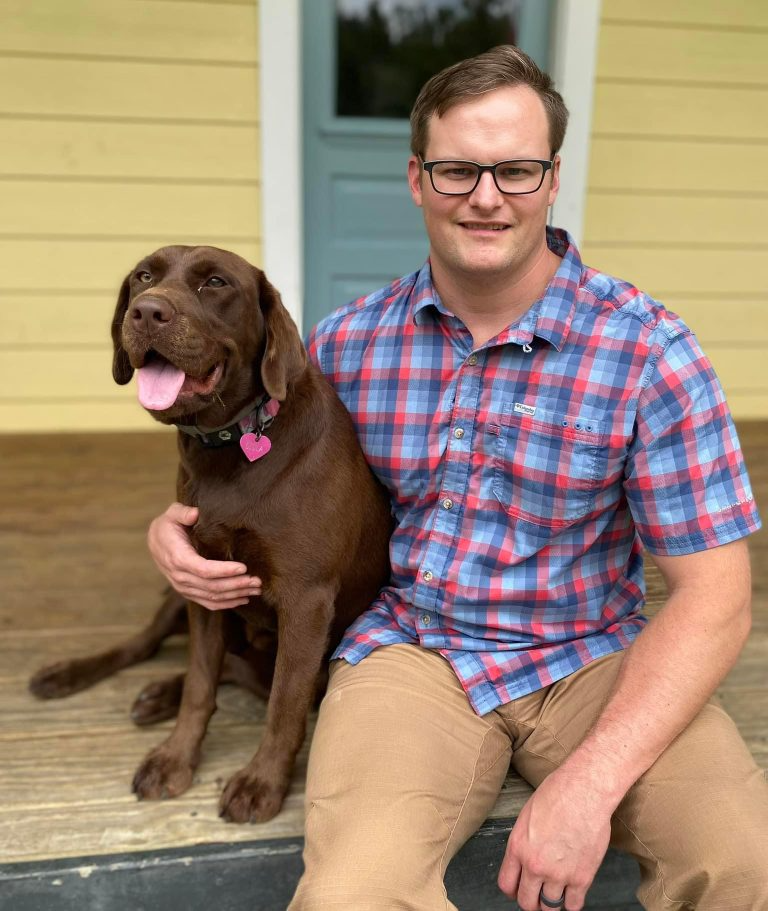 Dr. Fold and dog with pink collar sitting on porch.