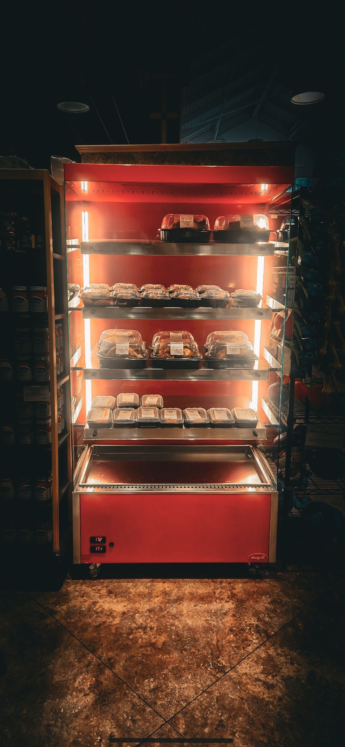 A red refrigerator filled with lots of food in a dark room.