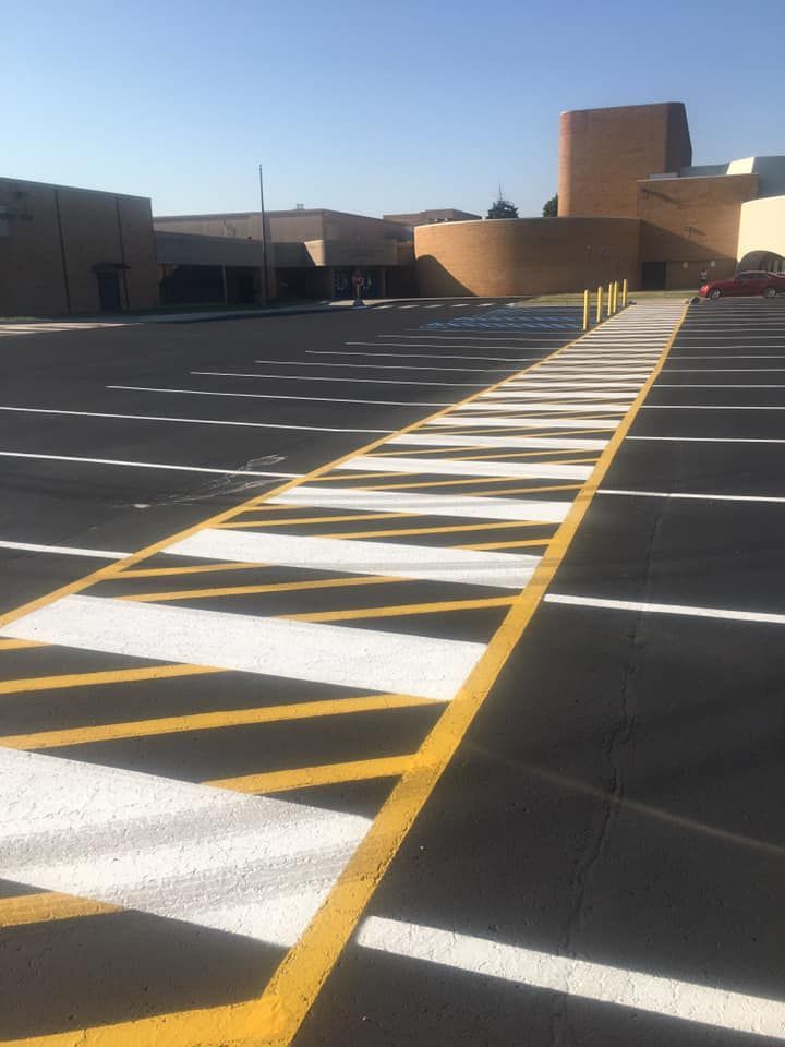 Parking lot with painted yellow and white crosshatch markings leading to a building.