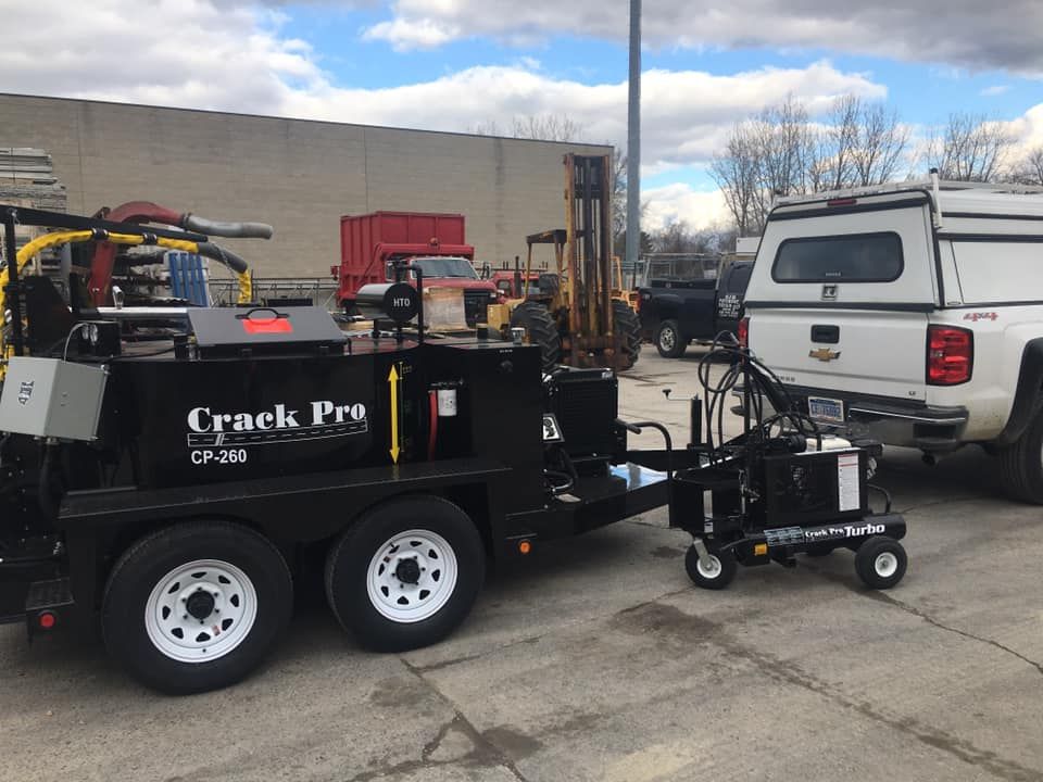 Asphalt with dark sealant filling cracks, yellow line, and tire tracks.