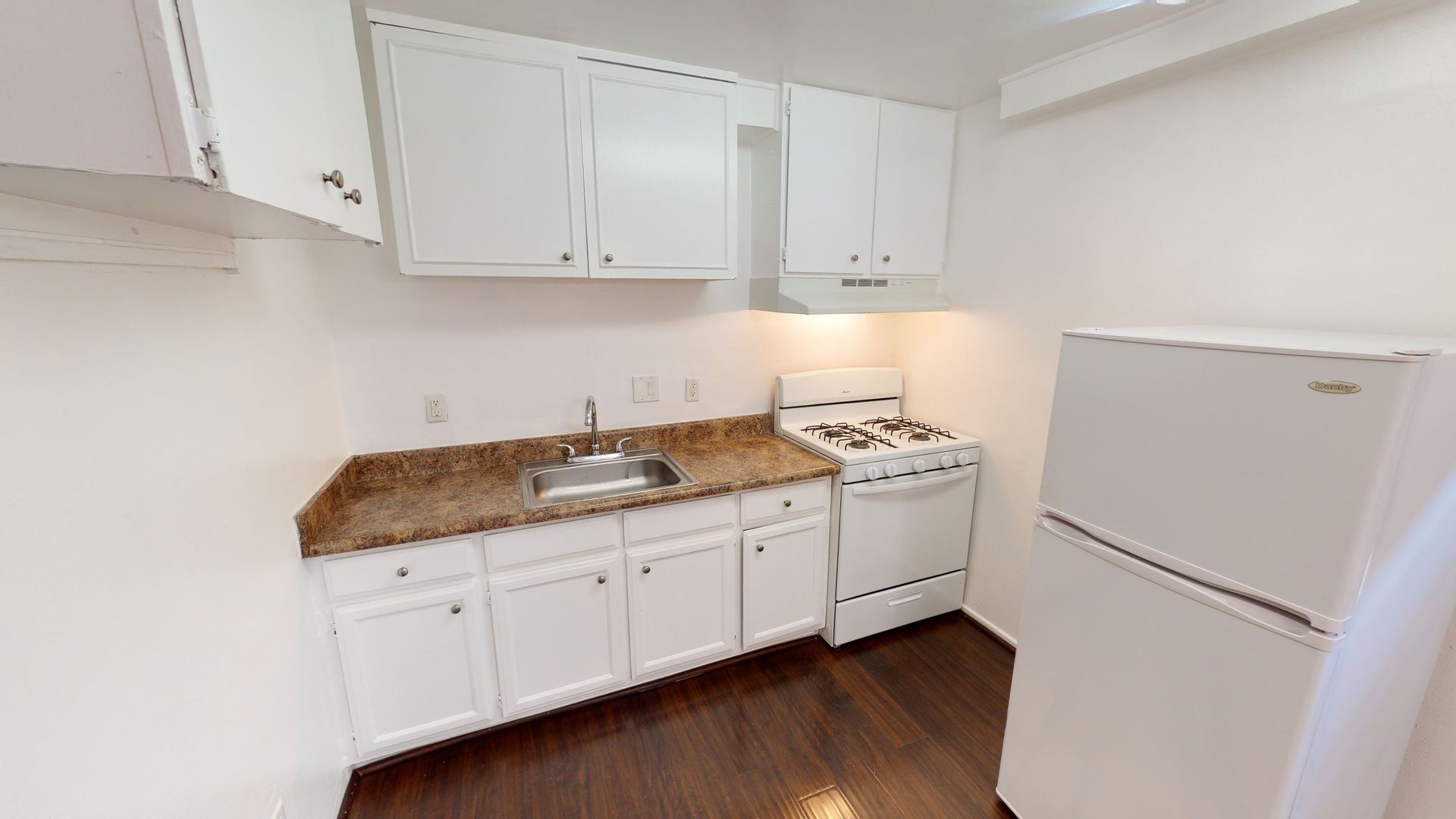 Small kitchen with white cabinets, appliances, and a brown countertop.