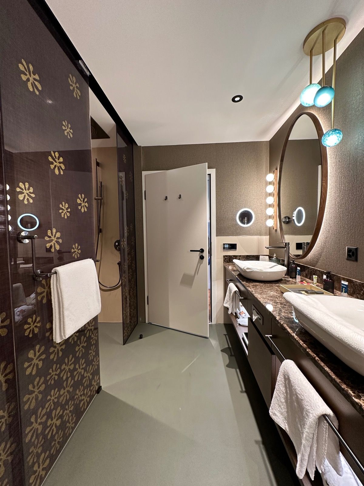 Badezimmer mit braun gemusterten Wänden, einem weißen Waschbecken und einem Duschbereich.