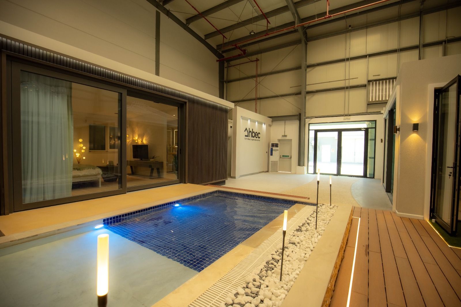 Innenpoolbereich mit Glasschiebetür zum Wohnbereich, blauem Pool, Holzdeck und neutralen Wänden.