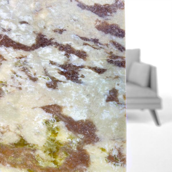 Nahaufnahme einer Marmorarbeitsplatte mit brauner und grüner Maserung, die ein graues Sofa teilweise verdeckt.