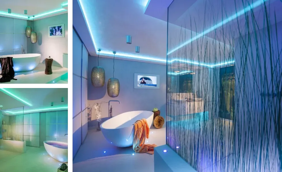 Ein modernes Badezimmer mit weißer Badewanne, Pendelleuchten und blauer und grüner LED-Beleuchtung.