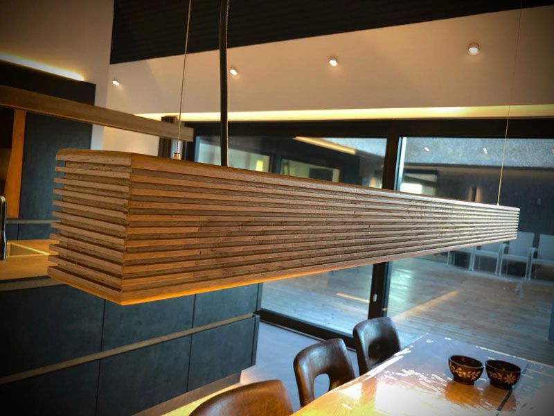 Rechteckige Pendelleuchte aus Holz über einem Esstisch. Moderne Innenarchitektur.