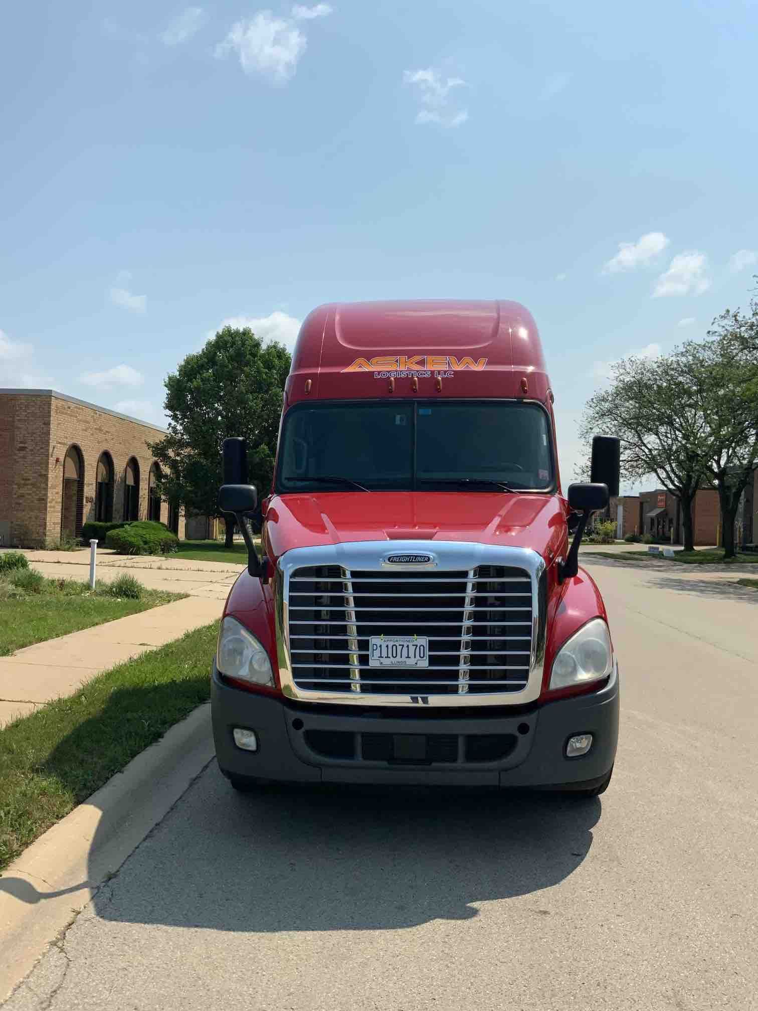 A red semi truck is parked on the side of the road.