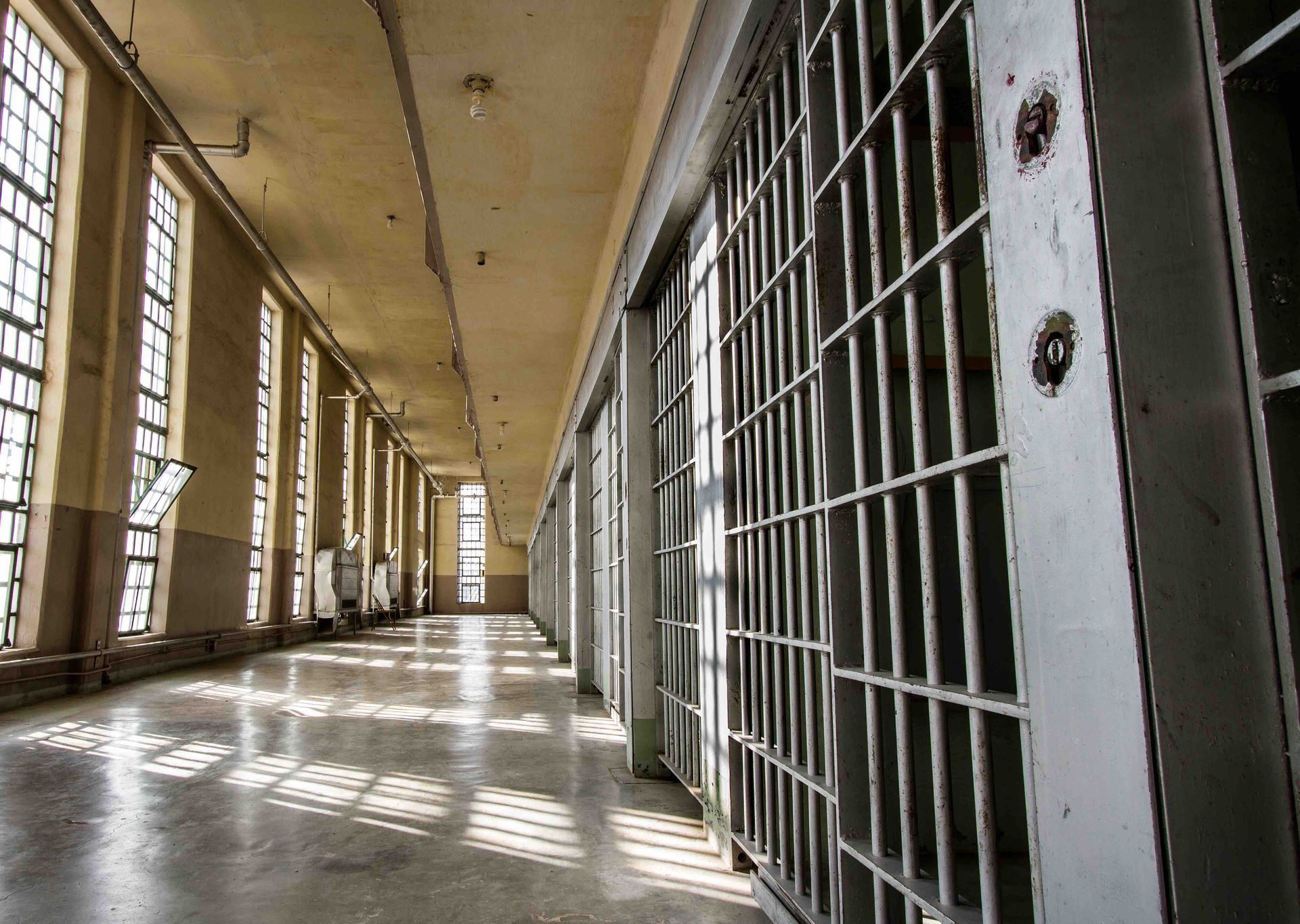 A long hallway in a prison with a lot of bars and windows.