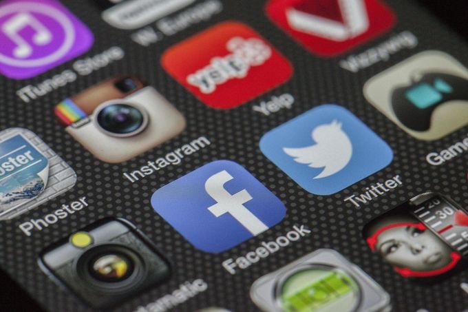 Close-up of a smartphone screen displaying social media app icons: Facebook, Instagram, Twitter, Yelp, and iTunes.