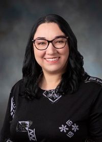 A woman wearing glasses and a black shirt is smiling for the camera.