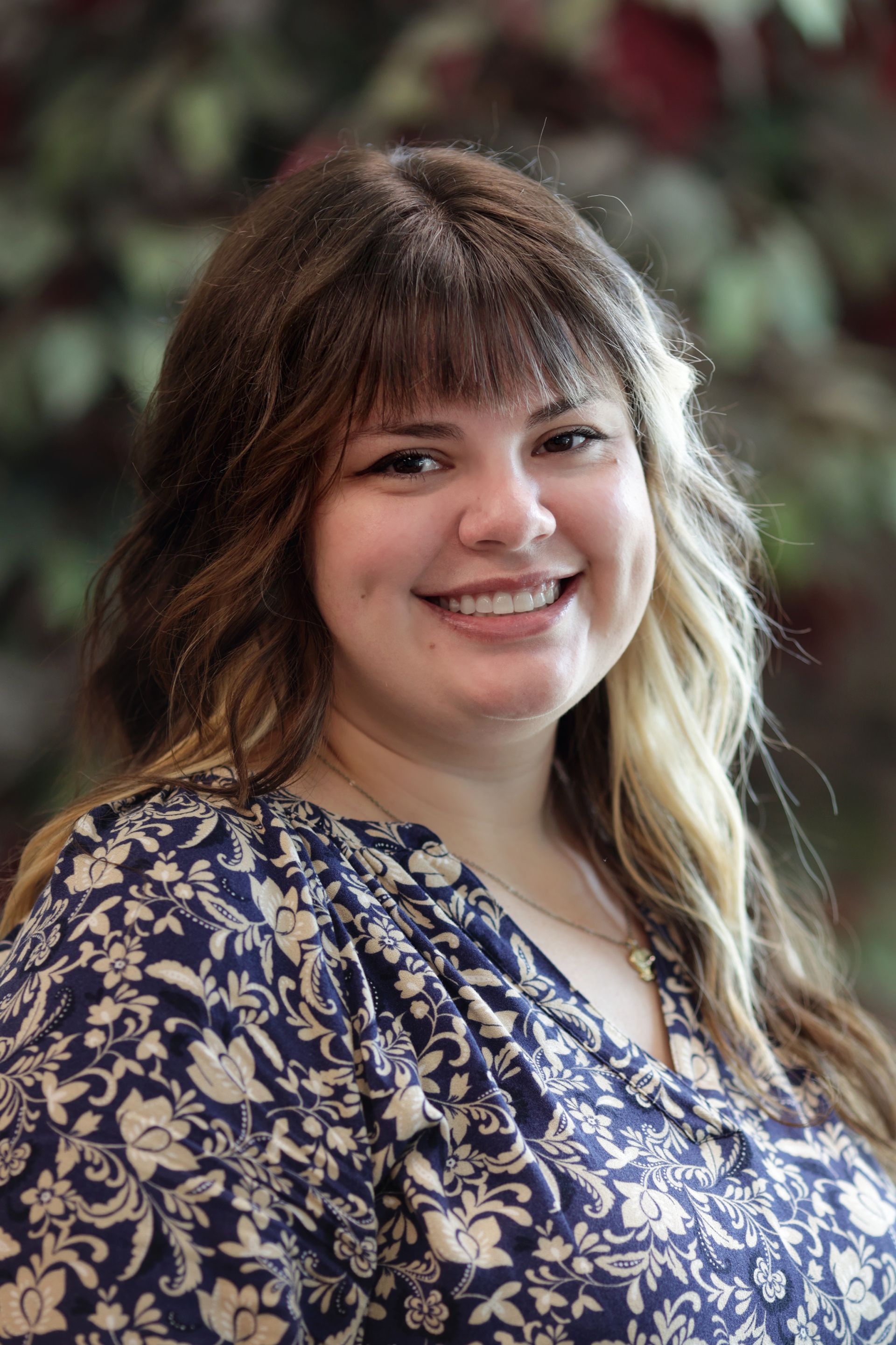 A woman wearing a pink sweater and a black shirt is smiling for the camera.