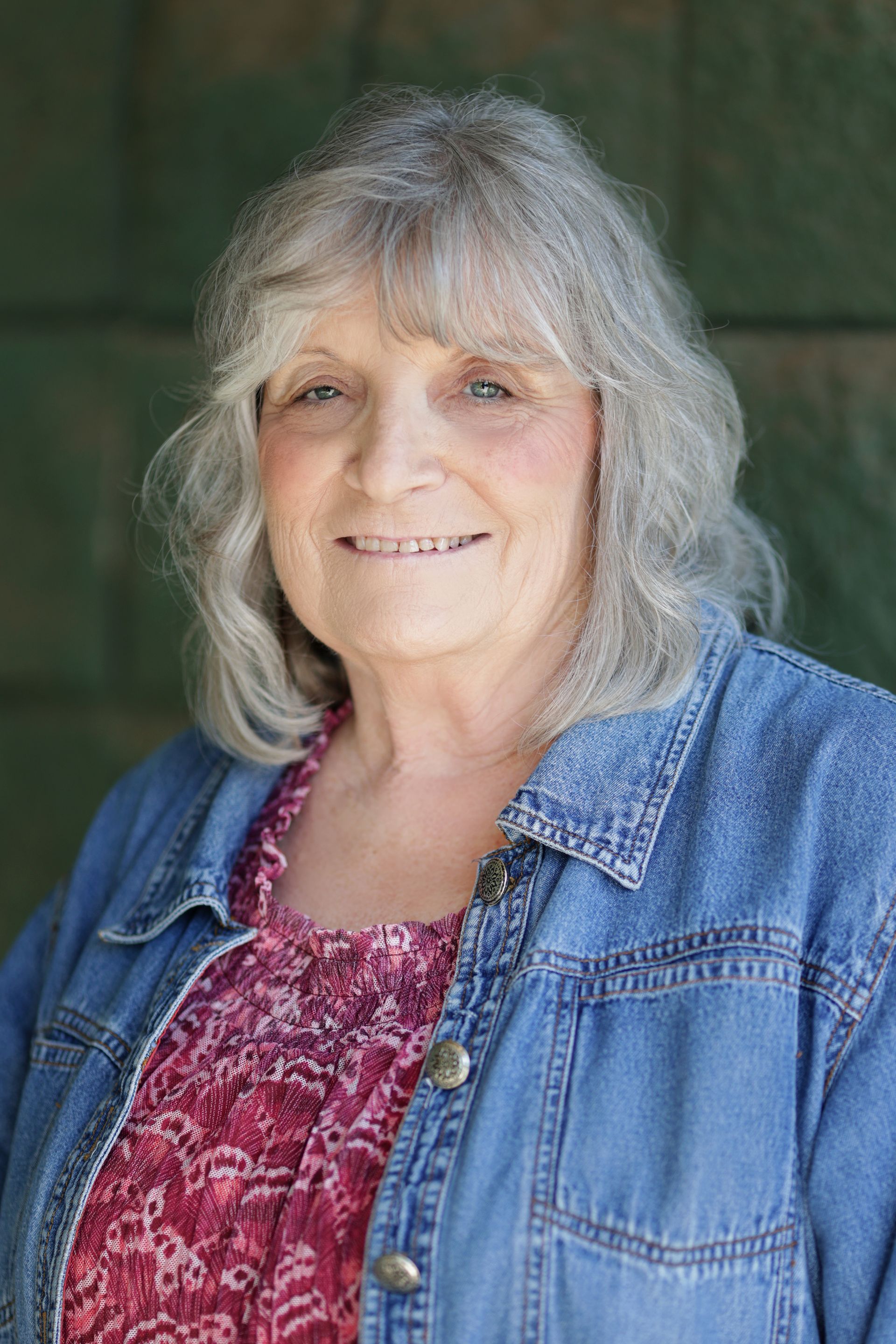 A woman in a purple shirt is smiling for the camera.