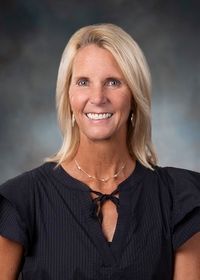 A woman in a black shirt is smiling for the camera.