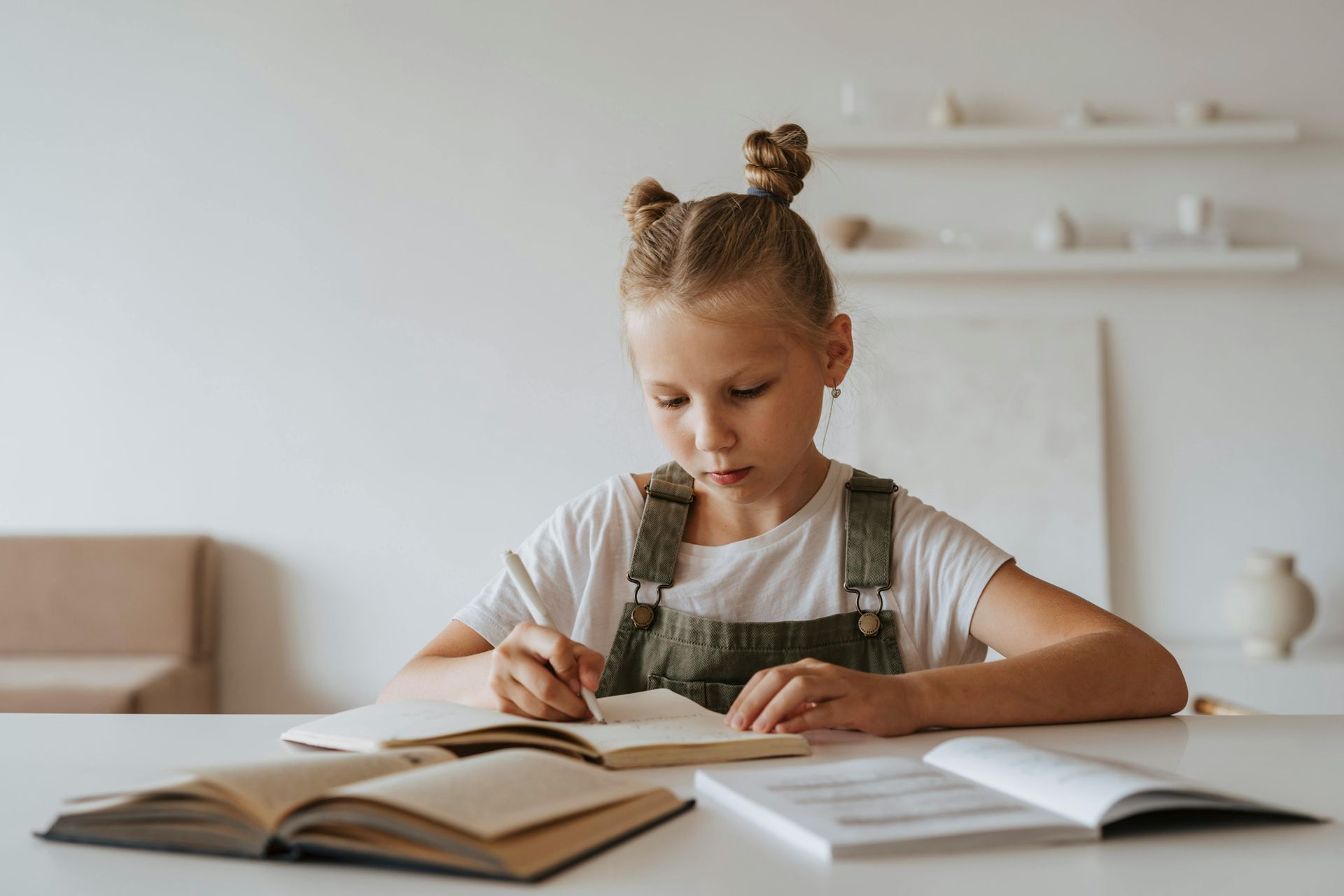A little girl is sitting at a table writing in a notebook.
