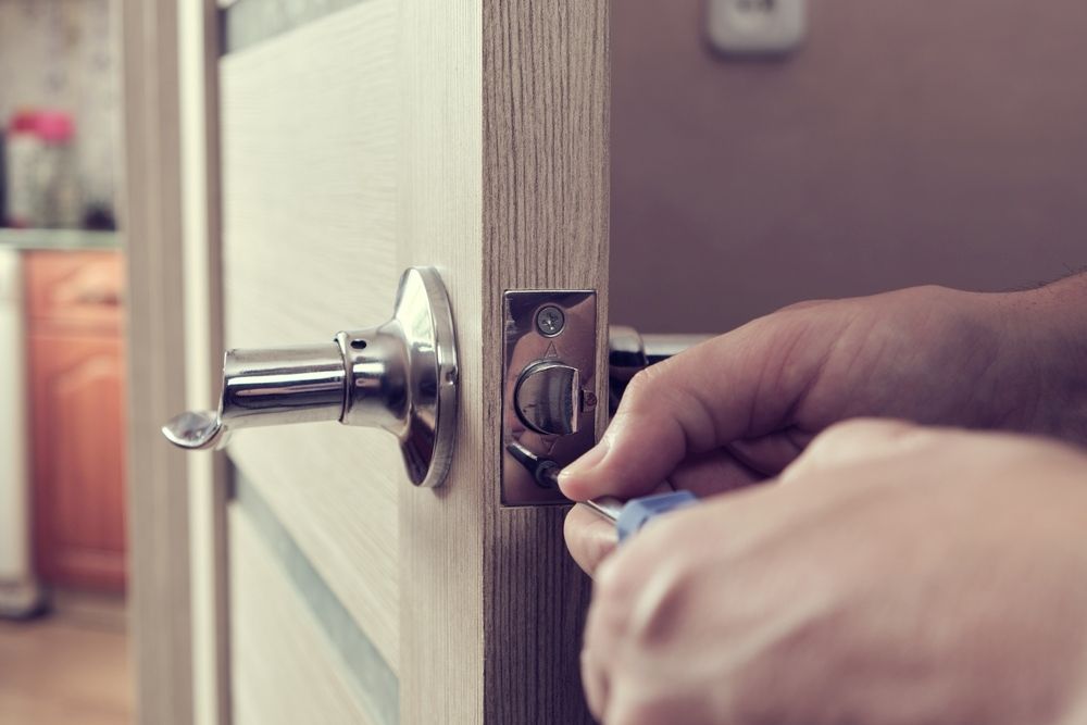 A Person Is Fixing a Door Handle with A Screwdriver — Century Locksmiths In Crows Nest, QLD