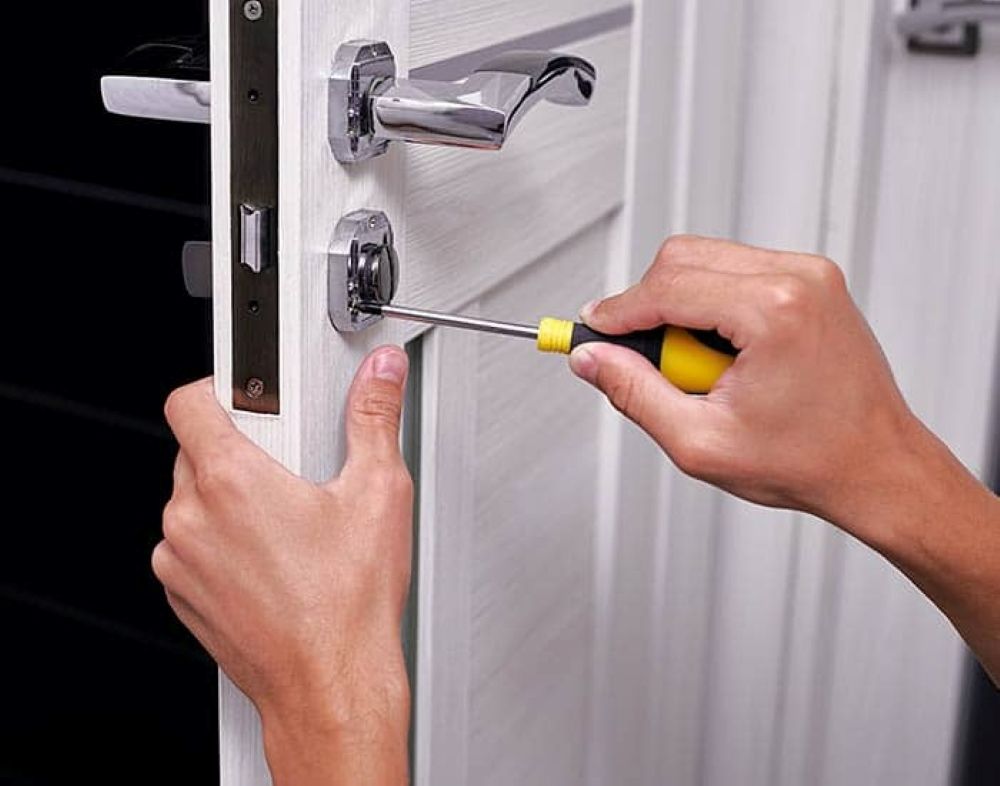 A Person Is Fixing a Door with A Screwdriver — Century Locksmiths In Toowoomba City, QLD