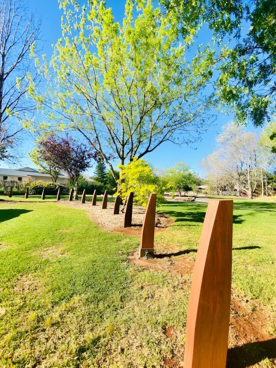 A Row of Wooden Posts in A Park with Trees in The Background — Century Locksmiths In Highfields, QLD