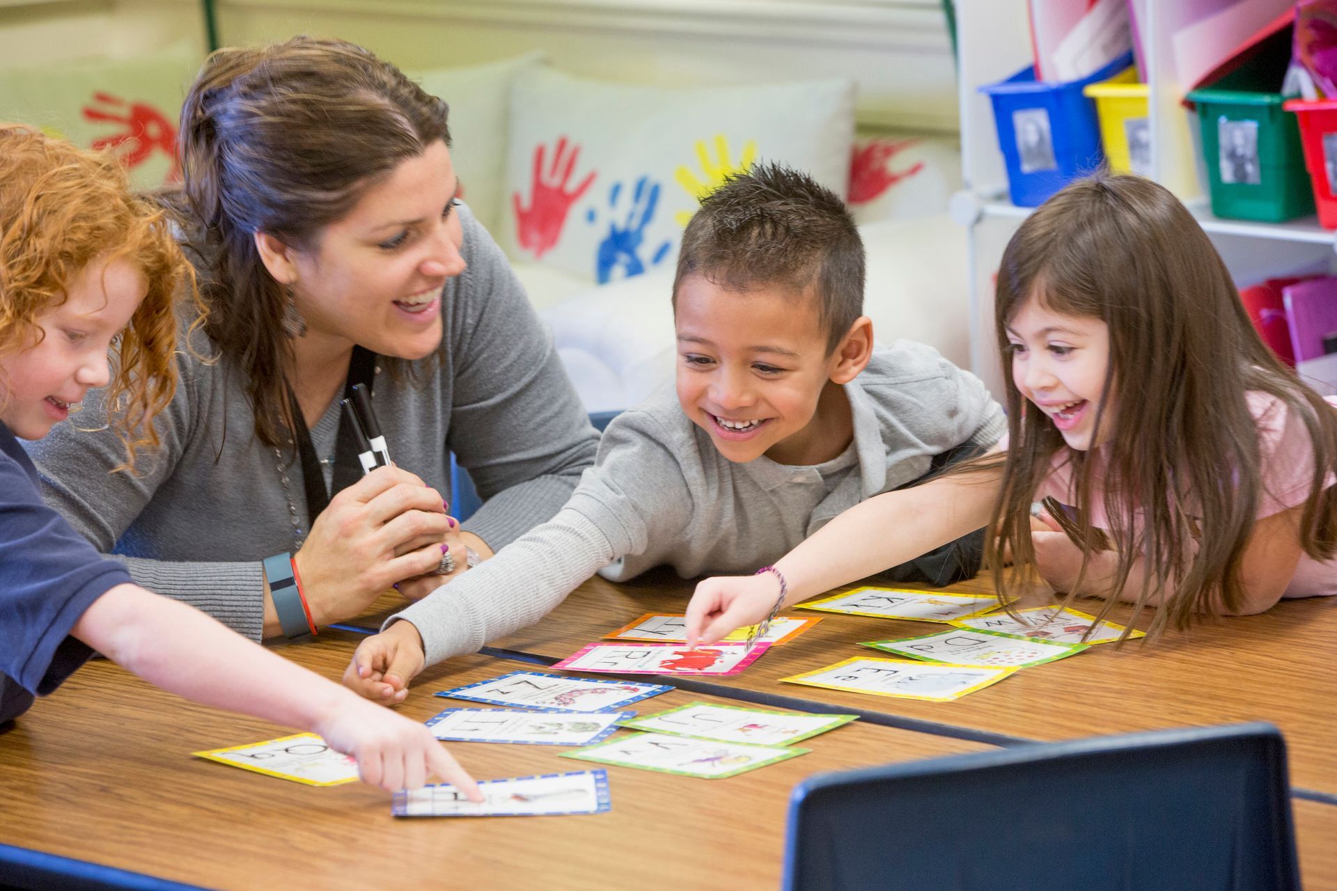 A group of children are playing cards with a teacher in a classroom.