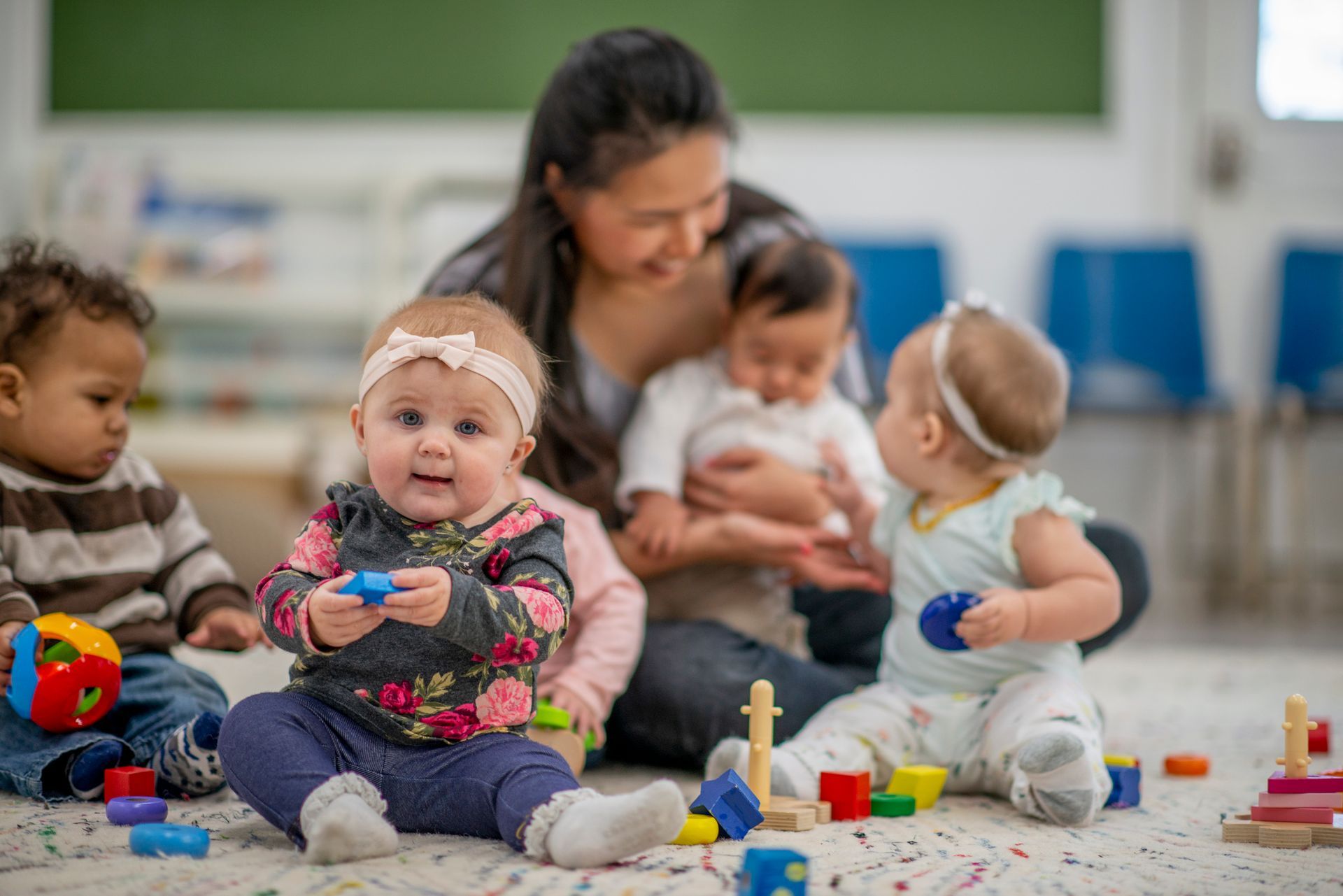 A group of babies are sitting on the floor playing with toys.