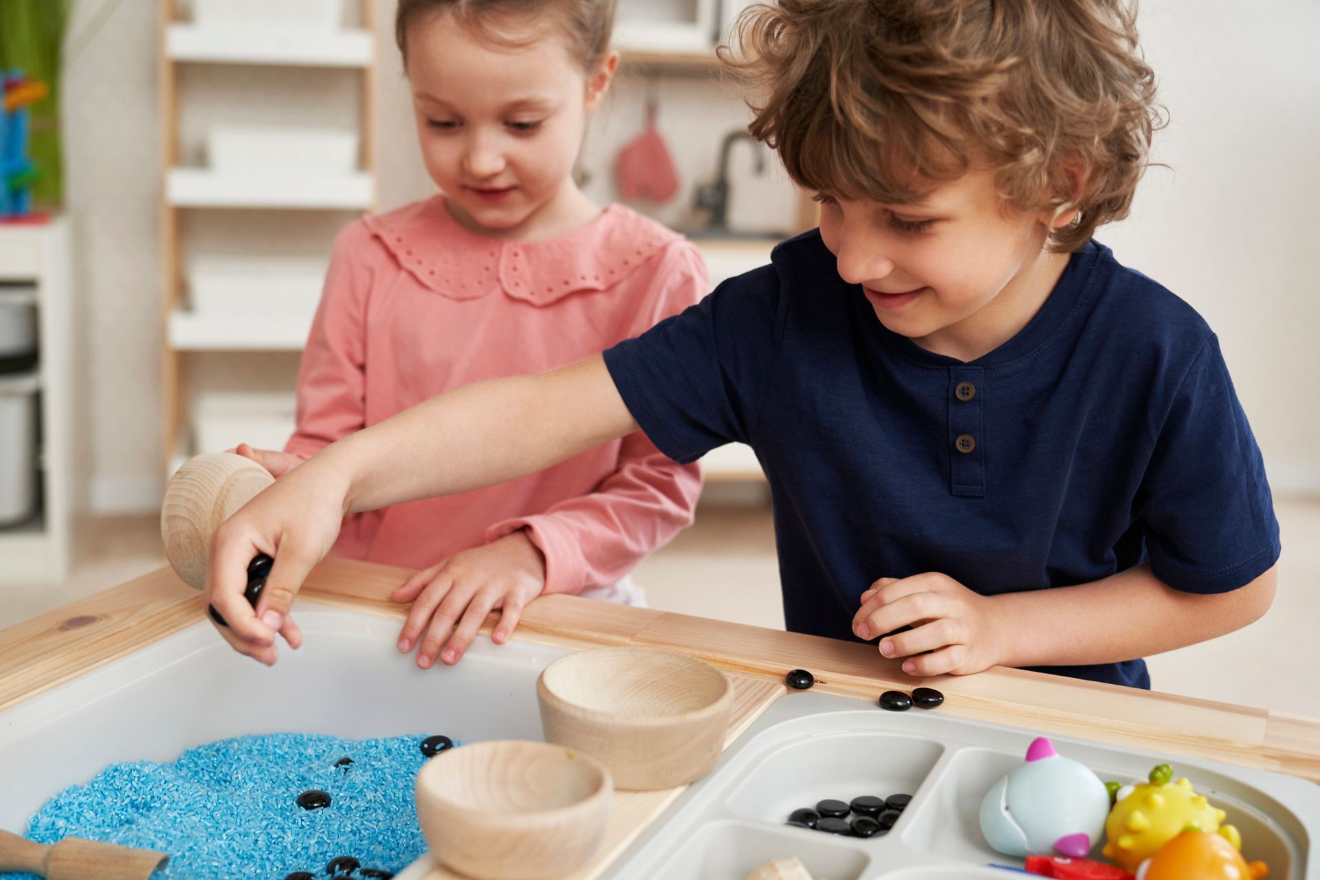 A boy and a girl are playing in a sensory bin.