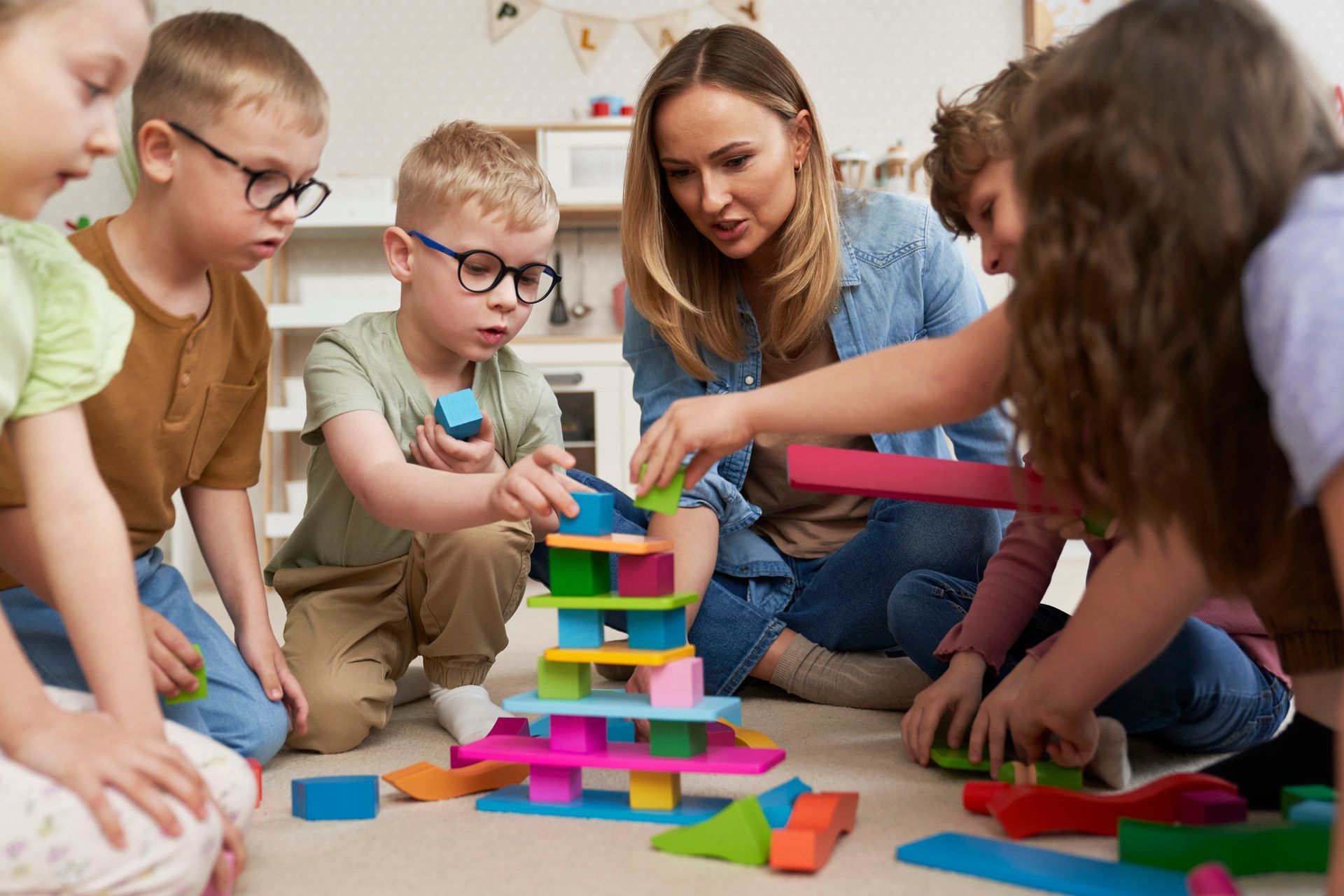A group of children are sitting on the floor playing with blocks.