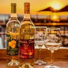 Three bottles of wine and two wine glasses are sitting on a wooden table.
